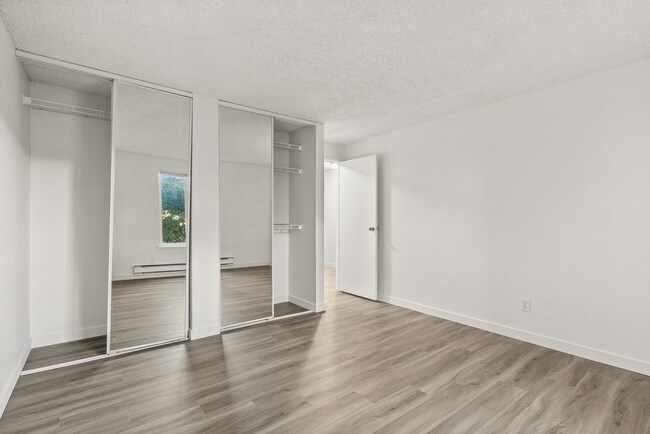 Unwind in a spacious bedroom featuring modern flooring and mirrored closets that enhance both storage and natural light. - Bay Ridge Apartments