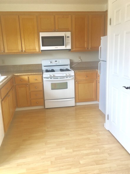 kitchen with gas stove and wood like flooring and marble counter top - 419 Sailfish Dr