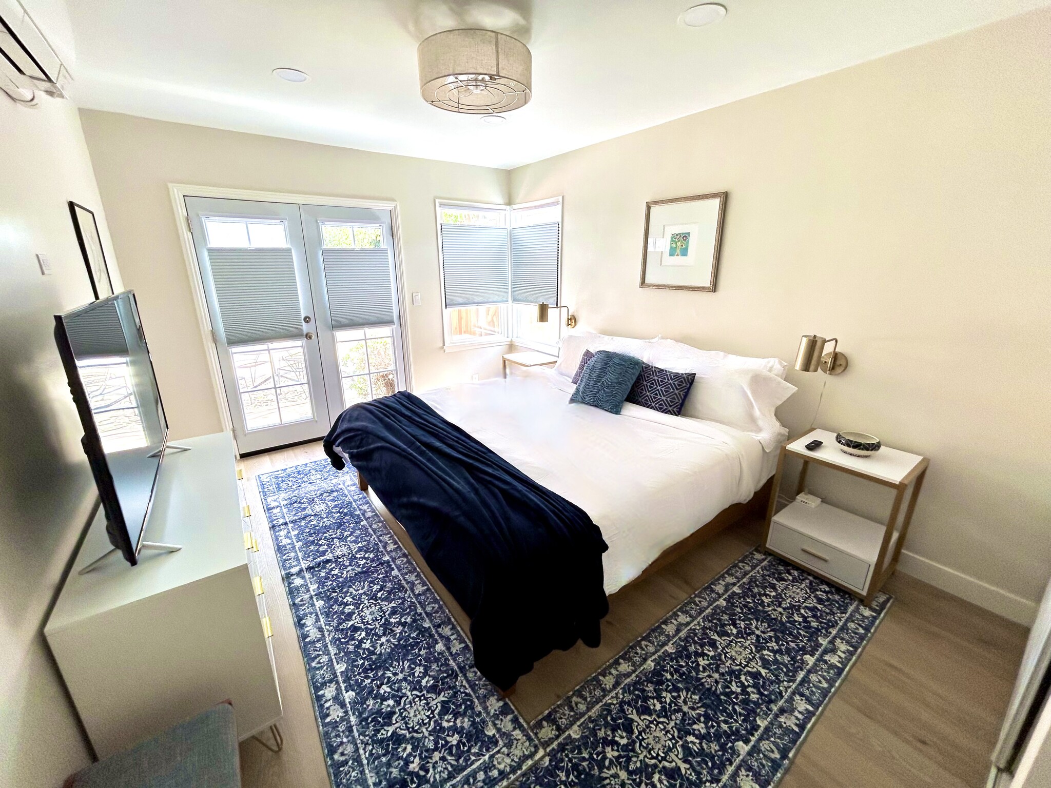 The primary suite has a comfy king Casper bed, smart 4K TV and French doors to the backyard. - 2824 S Orange Dr