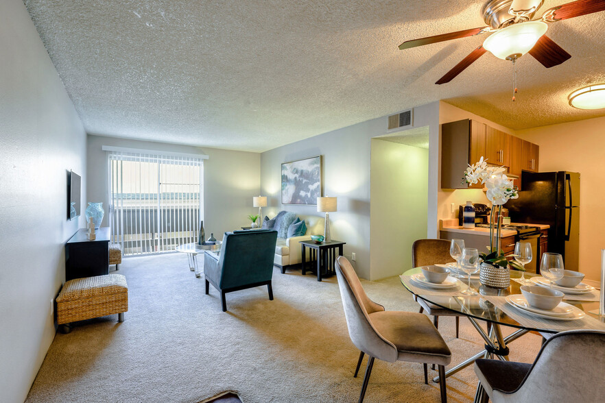 Model apartment dining area with a ceiling fan and a view of the living area and kitchen. - Montebello Gardens