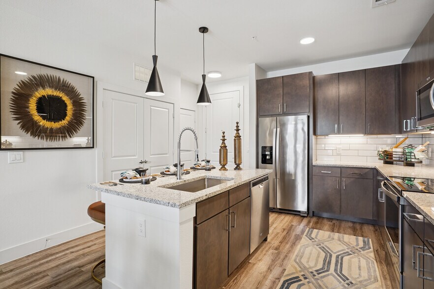 Kitchen with espresso cabinetry, speckled granite countertops, white tile backsplash, stainless steel appliances, and hard surface flooring - Avalon Castle Hills