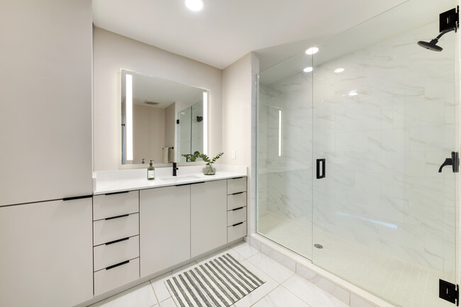 Tower Building - Renovated bath with white quartz countertop, light grey cabinetry, and tile flooring - Avalon West Palm Beach