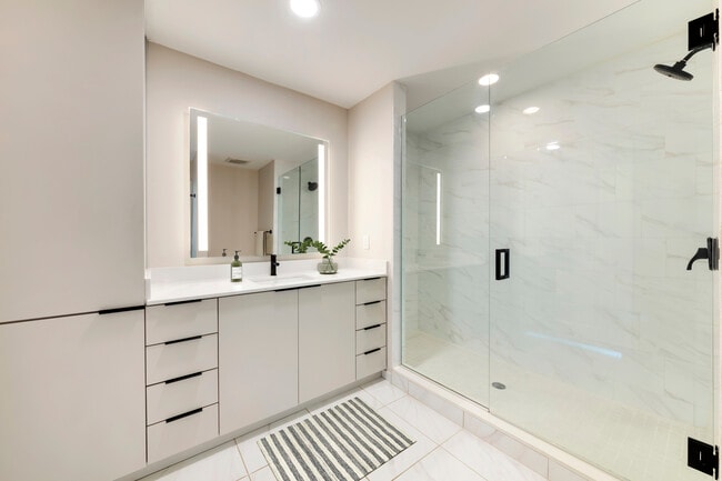 Tower Building - Renovated II bath with white quartz countertop, light grey cabinetry, and tile flooring - Avalon West Palm Beach