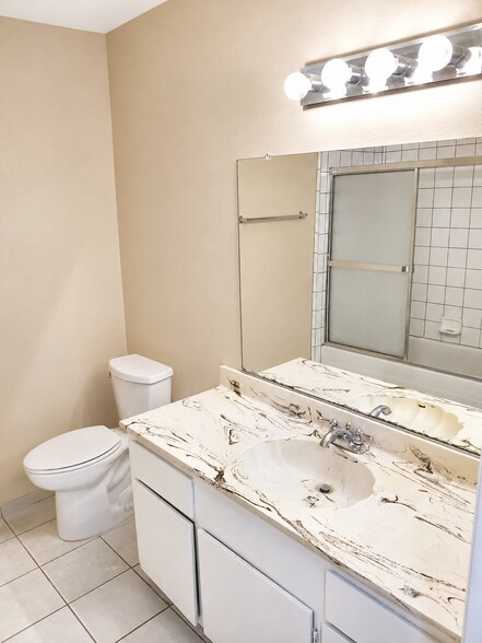 Clean guest bathroom with vanity, mirror, toilet, and tub/shower access. - 339 E Taft Ave