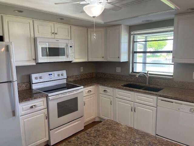 Granite countertops and white cabinets in the kitchen looks out to the backyard & water. - 2321 SE 5th Ct