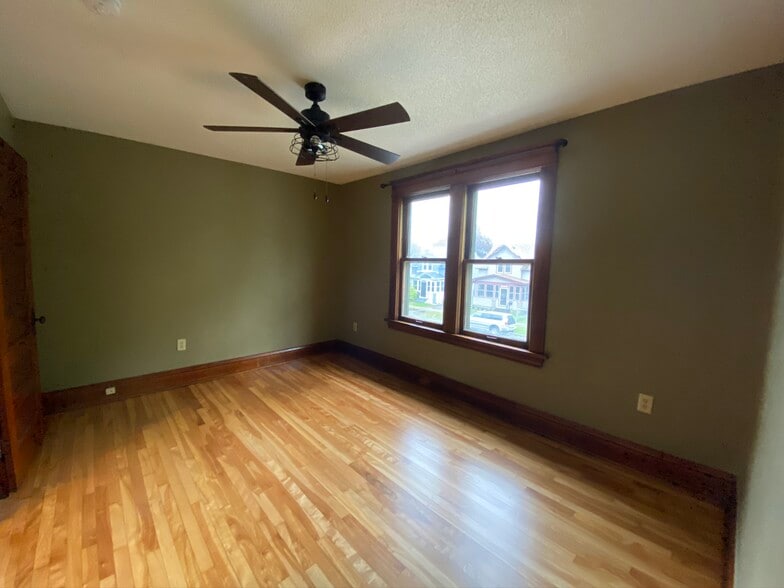 Large south-facing bedroom with a ceiling fan, closet, and original wood work - 783 Edmund Ave W