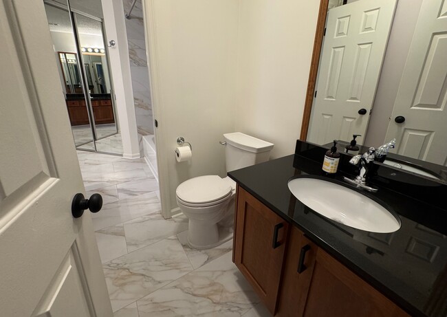 toilet with second sink and doorway into the large bathroom and walk-in closet - 209 14th St. NE #119