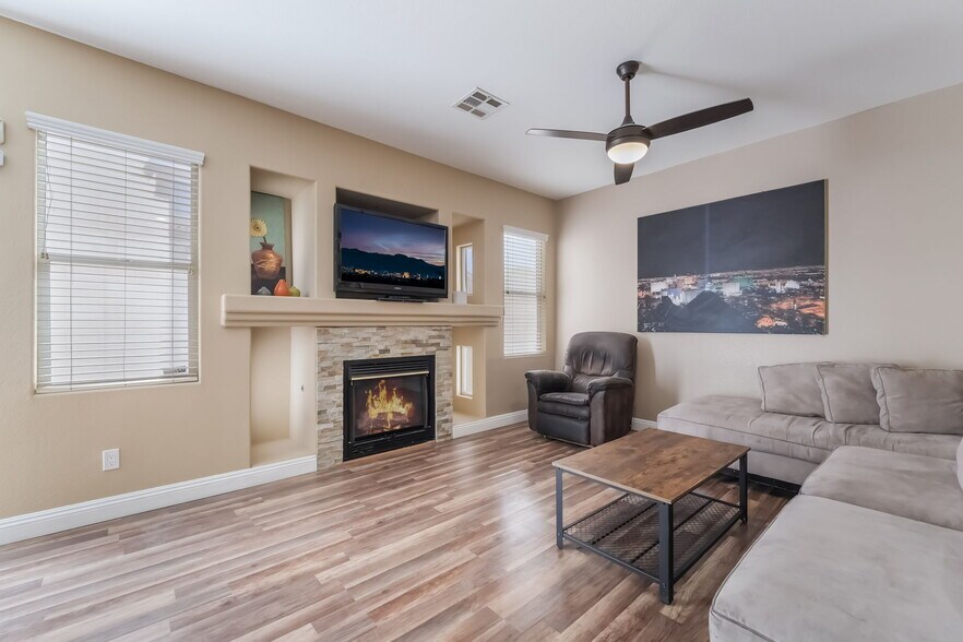Living area featuring wood finished floors, a stone fireplace, and a ceiling fan - 1179 Antoinette St