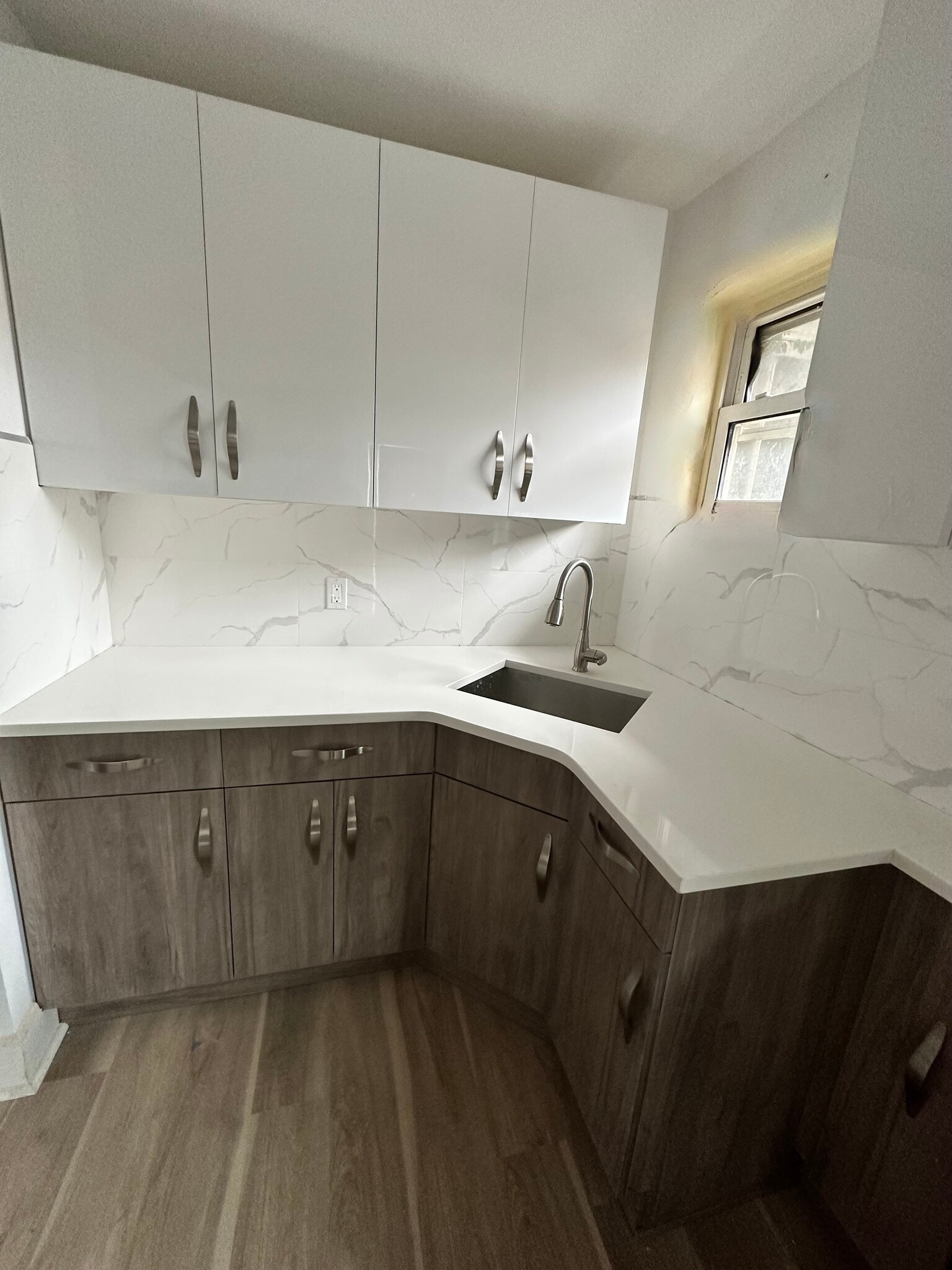 Sleek corner stainless steel sink positioned under a double window, inviting fresh air and bathing t - 328 High St