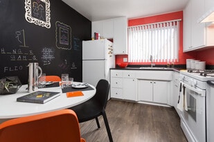 Classic Package II kitchen with white or black appliances, black laminate countertops, white cabinetry, and hard surface flooring (select homes)