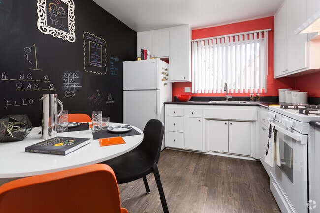 Classic Package II kitchen with white or black appliances, black laminate countertops, white cabinetry, and hard surface flooring (select homes)