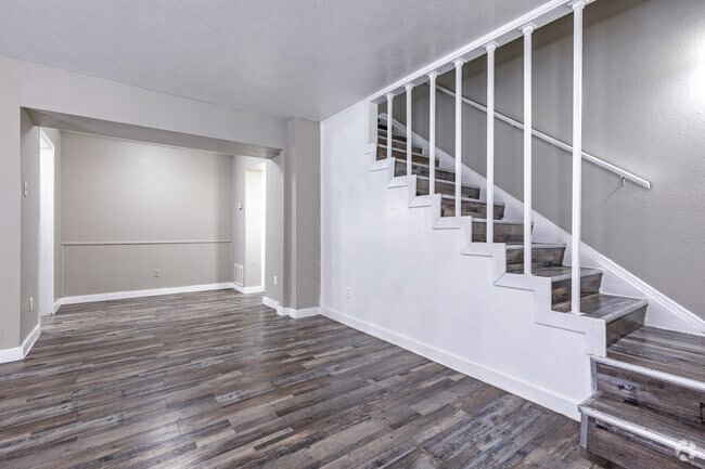 Spacious living room with open staircase and wood-style flooring - Vista Montana Apartments