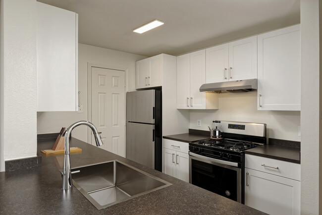 Renovated Package II kitchen with white cabinetry, dark grey laminate countertops, stainless steel appliances, and hard surface flooring - eaves Washingtonian Center