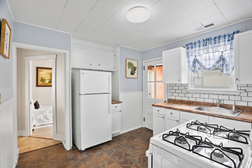 Kitchen with white cabinets and applicances, brand-new tile backsplash, and laminate countertop - 1710 B St