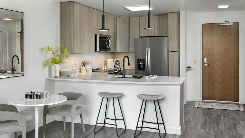 Apartment Kitchen with Stainless Steel Appliances, quartz counters and wood-like floors. - Griffis Cheesman Park