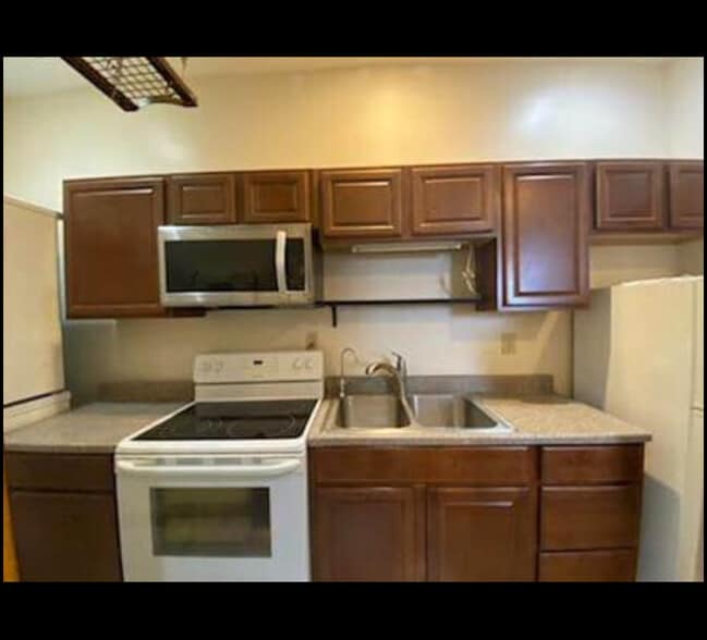 Gallery kitchen with pot rack above and storage space is plentiful in cabinets, as well some on top - 851 9th St