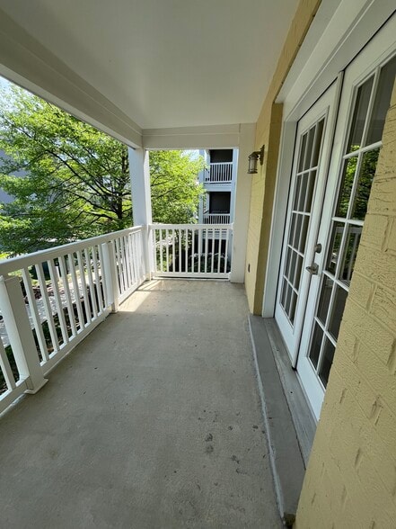 Private balcony with white railings and views of mature trees. - 4079 S Four Mile Run Dr