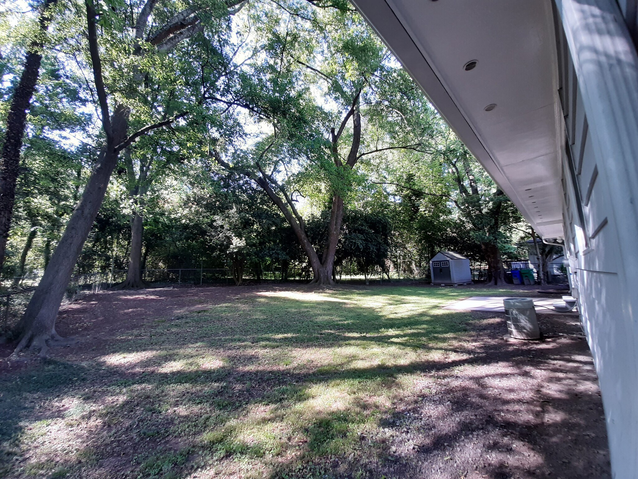 The large private backyard is surrounded by trees and a fence. - 2955 Fantasy Ln