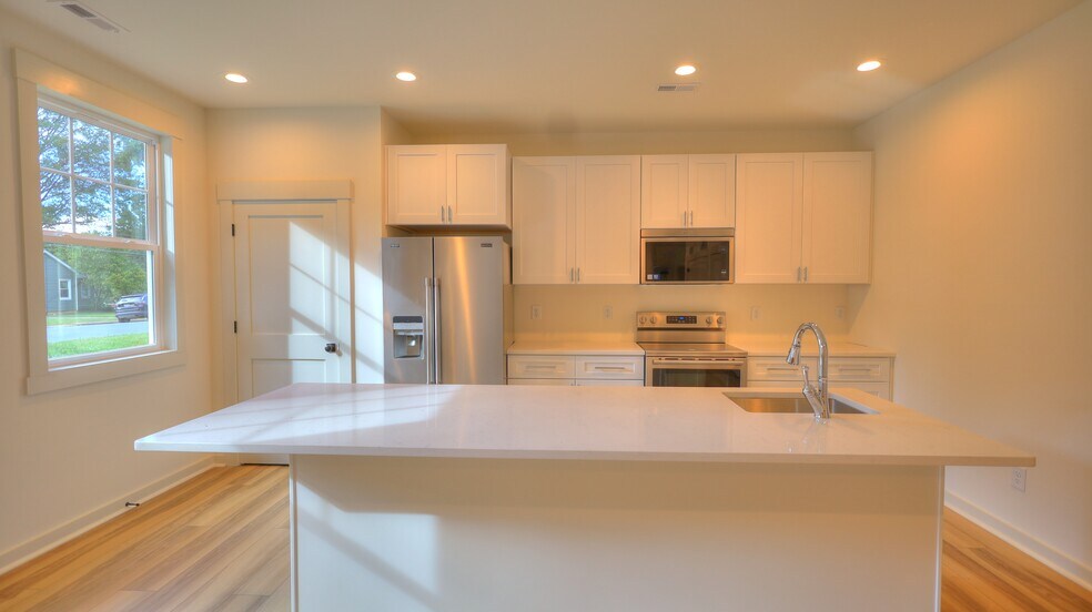 Unit A - Chef's kitchen with eat in island, quartz countertops and stainless appliances. - 345 W Stewart Ave