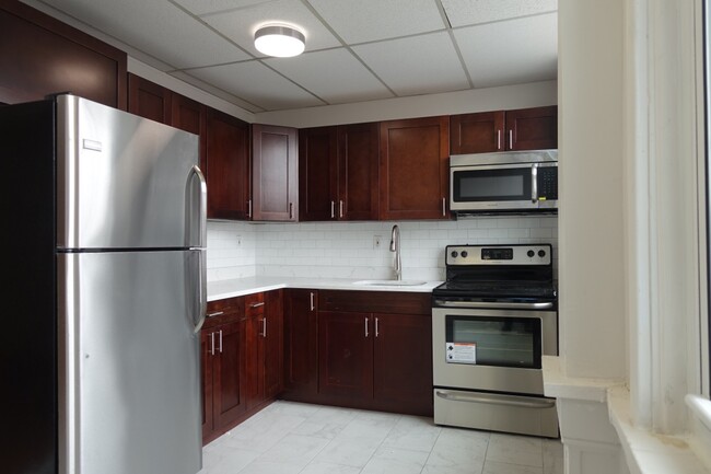 Kitchen with stainless steel appliances, double paned window next to stove for fresh airflow. - 5 E Broad St