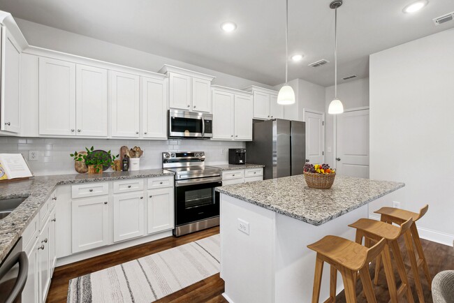 Spacious kitchen with an island, ample storage, and stainless steel appliances. - Alma Farms