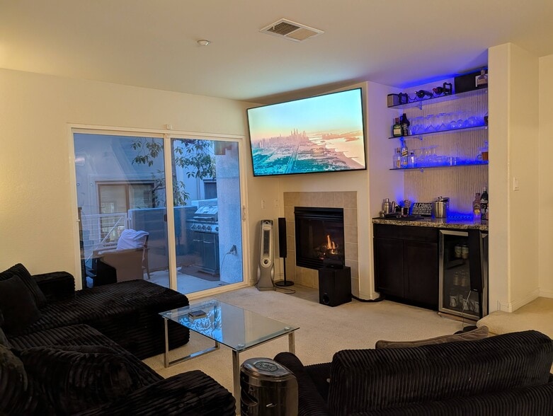 Living room TV, fireplace, bar, mini-fridge, and hidden entertainment center. Leads to balcony. - 3542 Shoreline Bluff Lane