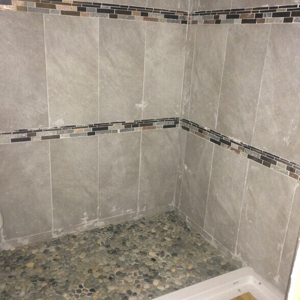 Bathroom shower has custom tile surround and has pebble floor. - 3000 Clarcona Road