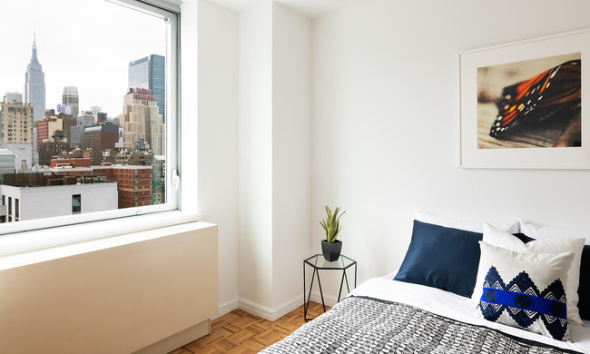 photo of 455 West 37th St Model Apartment 1508 view and bedroom staged with modern furniture - 455 W 37th St