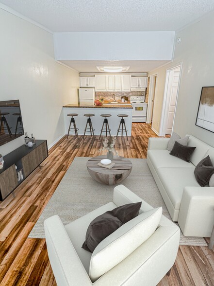 Open concept living and kitchen space with a central bar for seating and style - Whisperwood Apartments