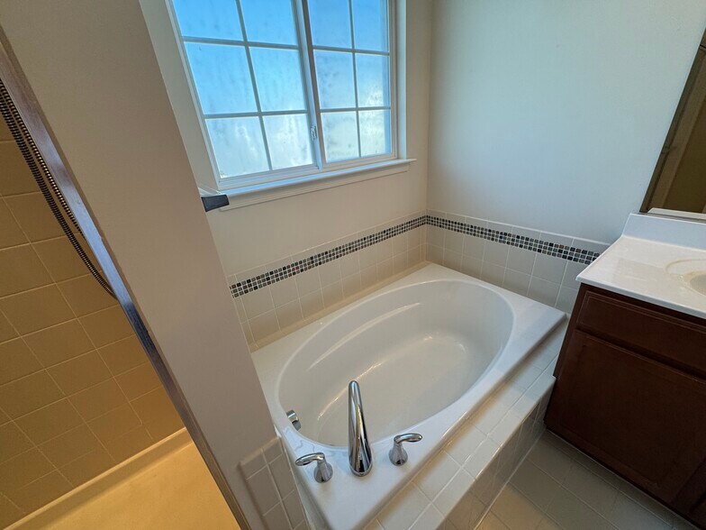 A large soaking tub with custom tile is another great primary bathroom feature! - 44520 Gray Wolf St