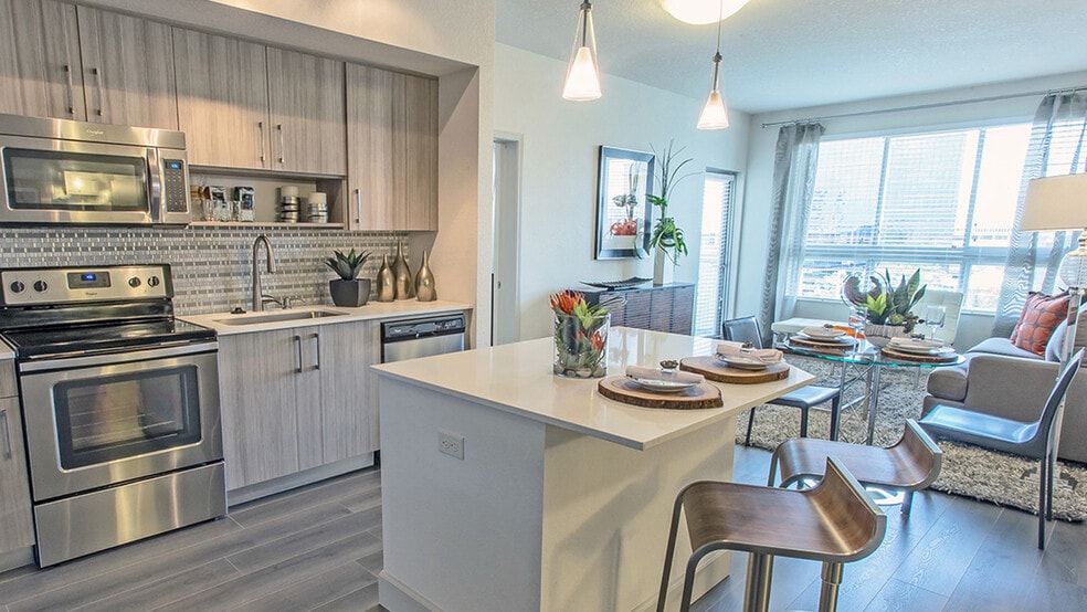 Modern luxury apartment kitchen with quartz island, stainless steel appliances, and open-concept dining and living area - Griffis North Olive