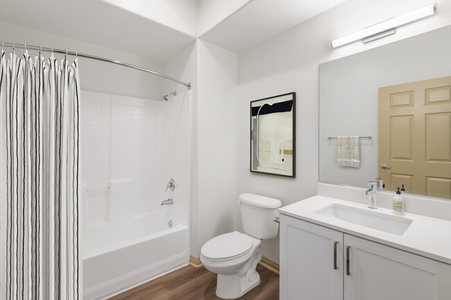 Renovated Package I bath with white speckled quartz countertop, white cabinetry, and hard surface flooring - Avalon Thousand Oaks Plaza