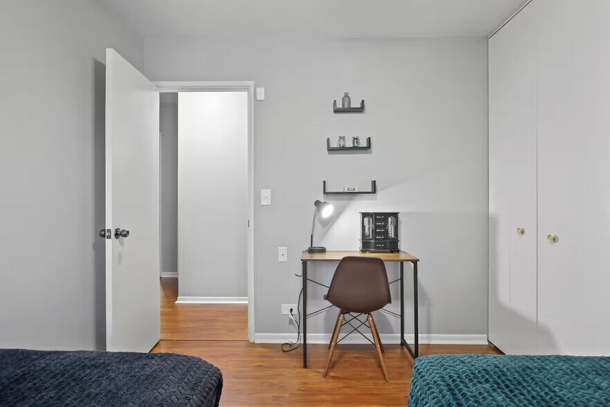Bedroom 3 with 2 single beds, dedicated work space with table, lamp and chair and closet space. - 1002 Juniper Ln