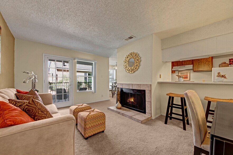 A living room with fireplace, glass door out to the patio, and breakfast bar - Cypress Pointe
