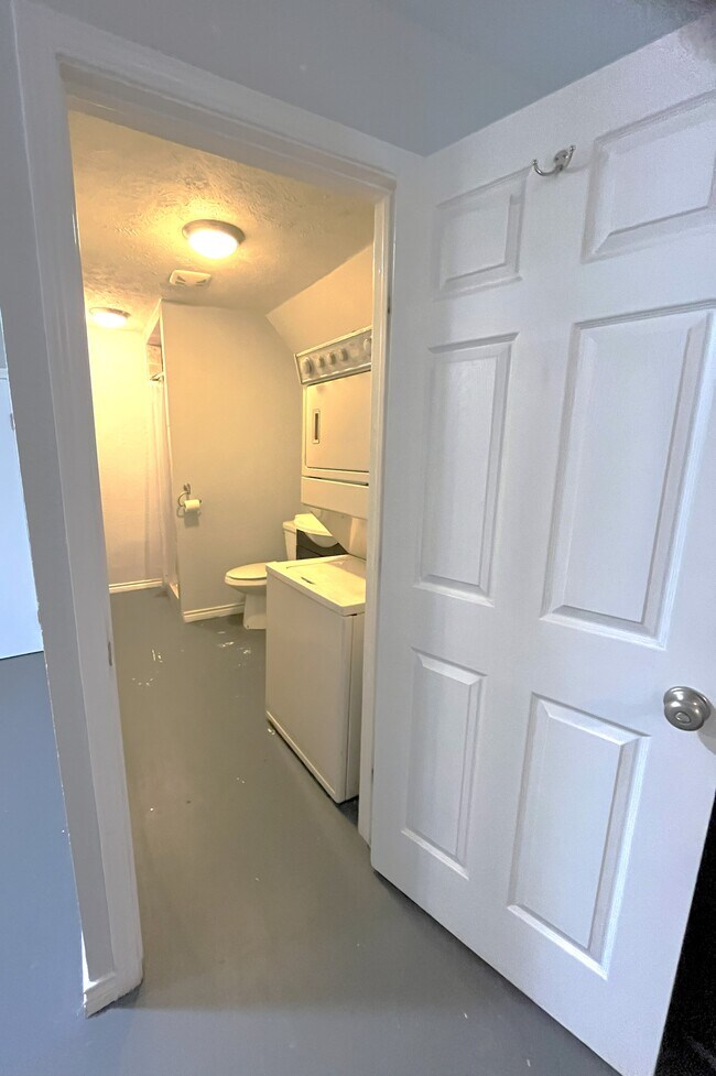 Bathroom with utility area that includes stacked washer/dryer unit. - 1127 Walling St