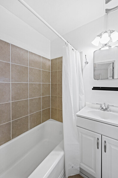 Bathroom has been redone with white subway tile. - 5107 Leeds Ave