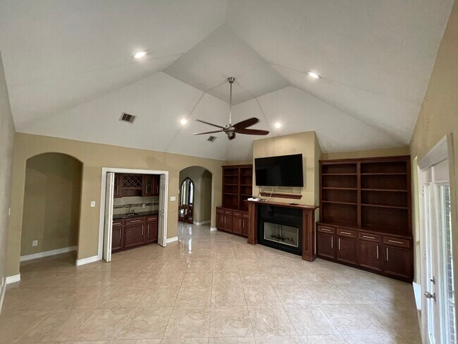Living room with wet bar, high vaulted ceilings, recess lighting, custom wood cabinets, chimney - 600 River Bend Dr