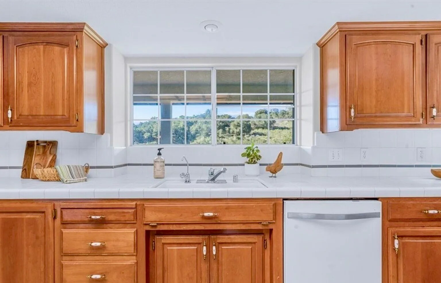 Cheery cabinetry and white tile countertops (note: kitchen faucet has been updated). - 221 Appy Way