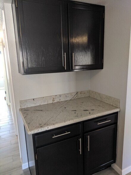 Hall Cabinets and storage area with granite counter tops, stained wood, and brushed nickel Tbar handles - 14101 N 78th Dr