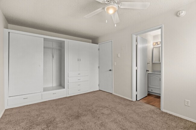 Cozy bedroom featuring generous built-in storage, soft carpeting, and direct access to the bathroom. - Highland Court Apartments
