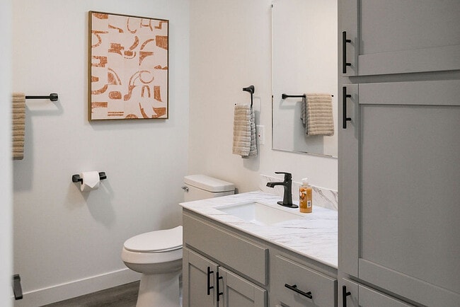 Sleek modern bathroom with elegant fixtures, marble countertop, and abstract wall art, blending style with functionality. - Highland Park Apartments
