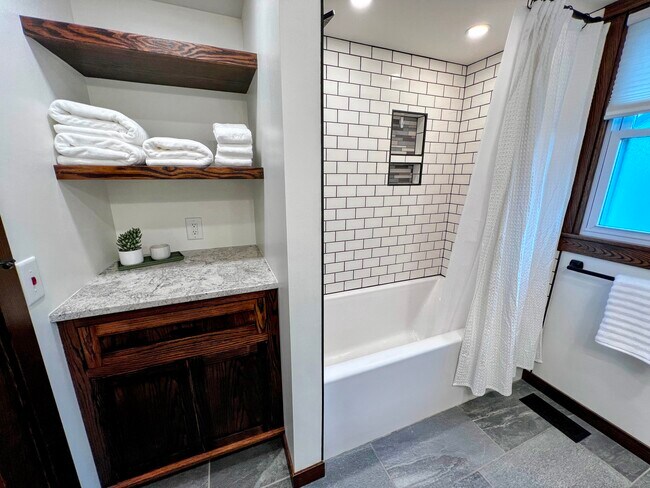 The shower is tiled and behind the door is additional shelf and cabinet storage. - 228 W Lexington Blvd