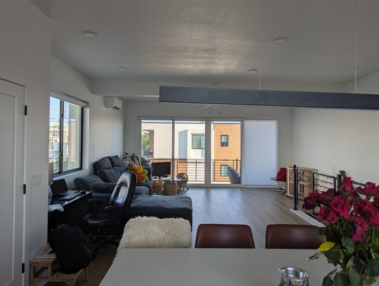 Living room with a ceiling fan, light wood-style flooring, recessed lighting, and a wall mounted air - 44 W Iko Ave