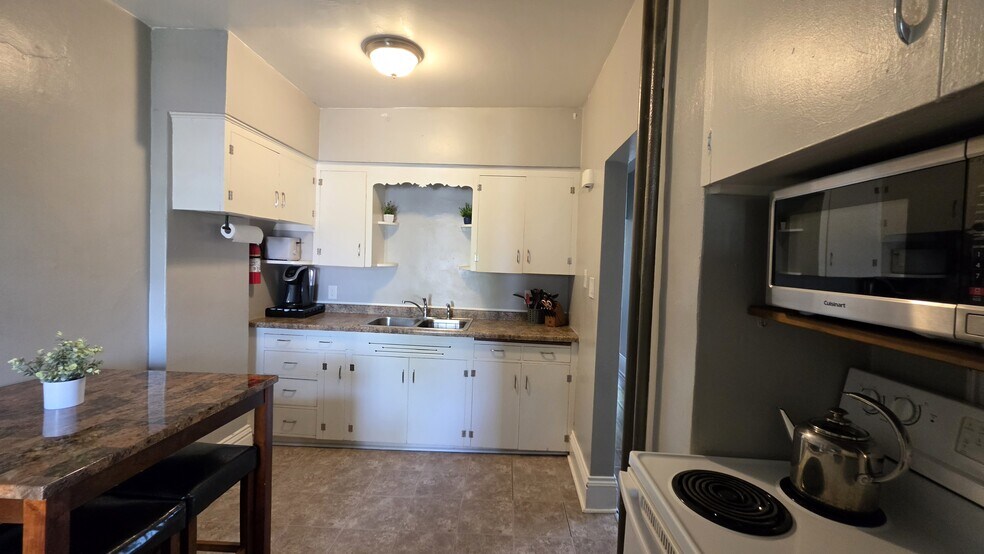 Fully equipped kitchen with ample cabinet space, full-size appliances, and dining area. - 822 E 4th St