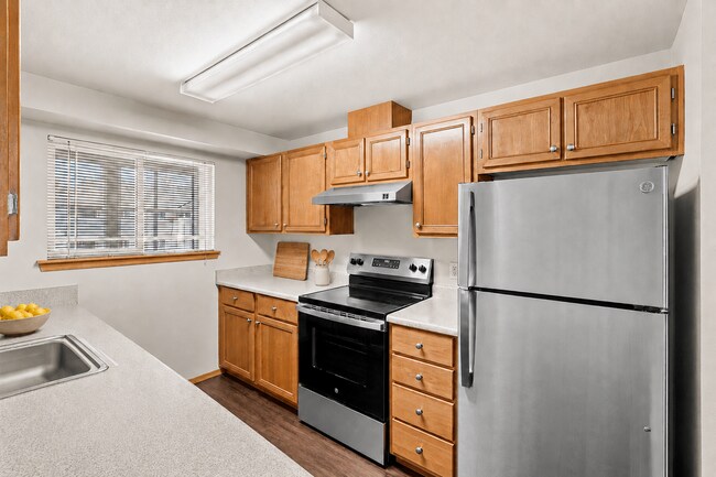 Bright, inviting kitchen with warm wood cabinetry, generous counter space, and stainless-steel appliances. - Villas at Lawrence