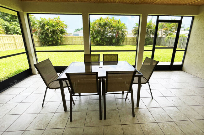 Outdoors dining table and chairs in a spacious screened patio - 722 SE Thanksgiving Ave