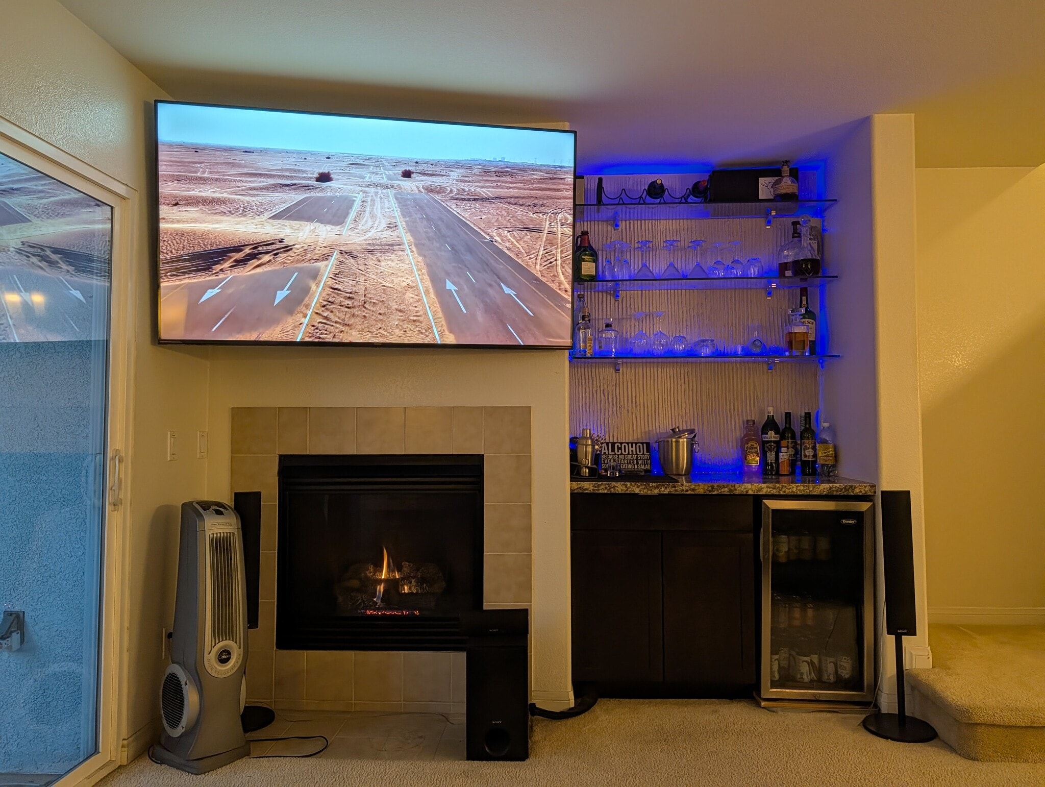 Living room TV, fireplace, bar, mini-fridge, and hidden entertainment center. - 3542 Shoreline Bluff Lane