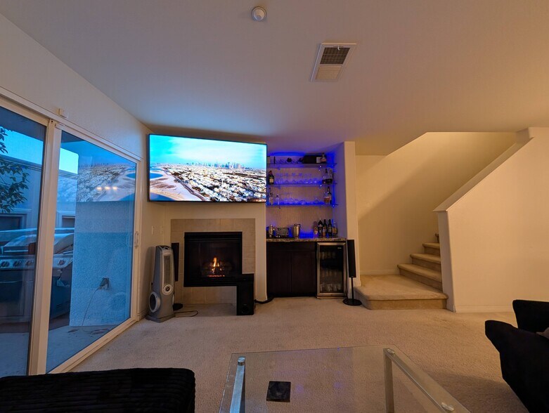 Living room TV, fireplace, bar, mini-fridge, and hidden entertainment center. - 3542 Shoreline Bluff Lane