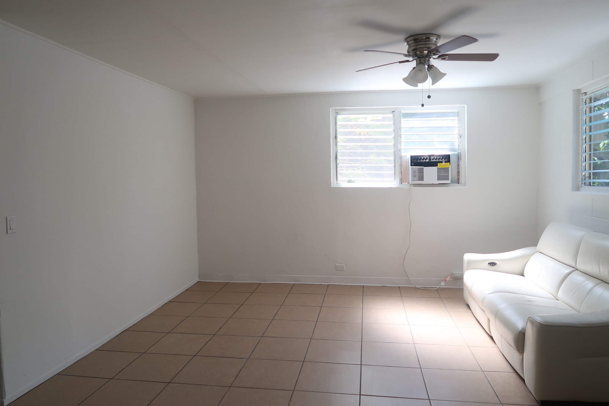 Large living room, furnished with electric reclining leather couch, and AC - 1739 Kamohoalii St