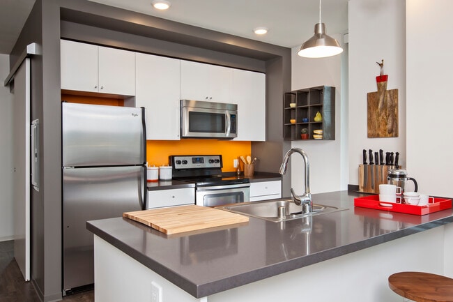 Kitchen with white cabinetry, chrome countertop and stainless steel appliances - AVA 55 Ninth